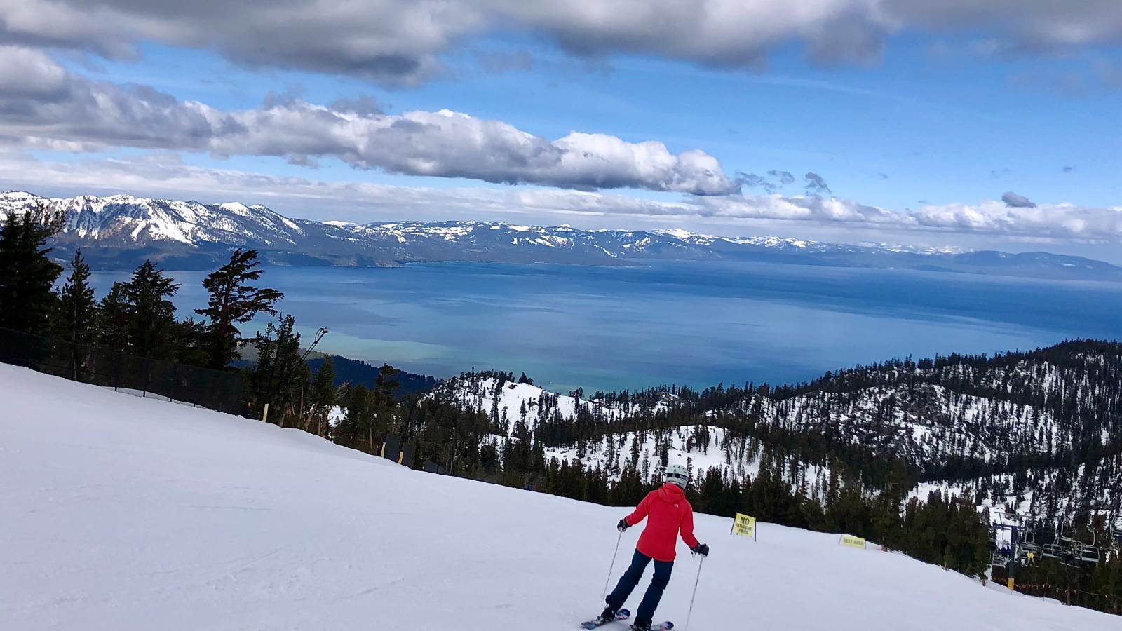 A photo of a person skiing with Lake Tahoe in the background and a dark cloudy sky