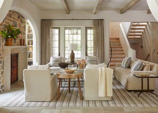 Farmhouse decor ideas, cozy cream living room with stone flooring, striped rug, armchairs and sofas gathered around coffee table and fireplace