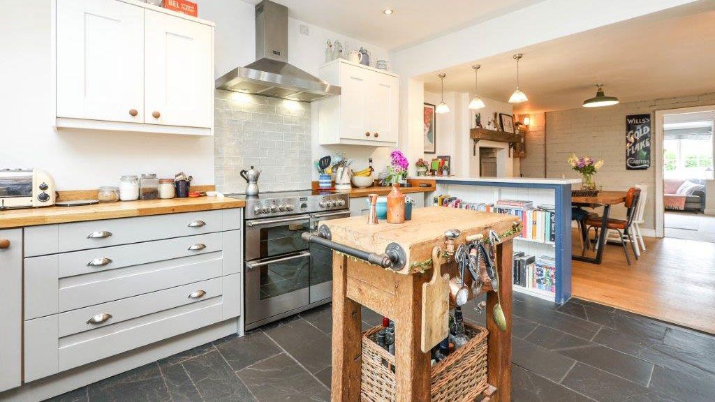 Shaker-style kitchen with rustic butcher&#039;s block and slate floor with modern range cooker