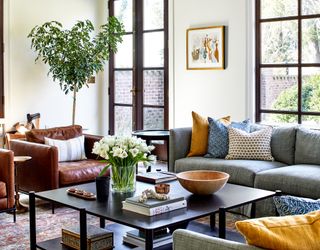 living room with grey sofa and accent brown leather chair, large windows and throw pillows