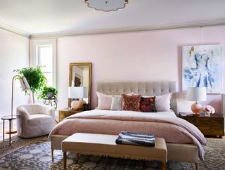 pink bedroom with double bed and tub armchair and ottoman