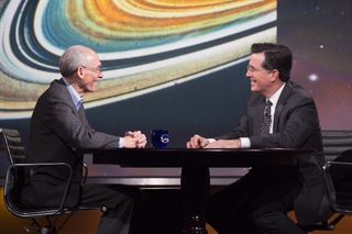 Voyager project Ed Stone speaks with host Stephen Colbert against a backdrop image of Saturn's rings on Dec. 3, 2013