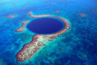 huge blue hole in the middle of the ocean with small islands surrounding it