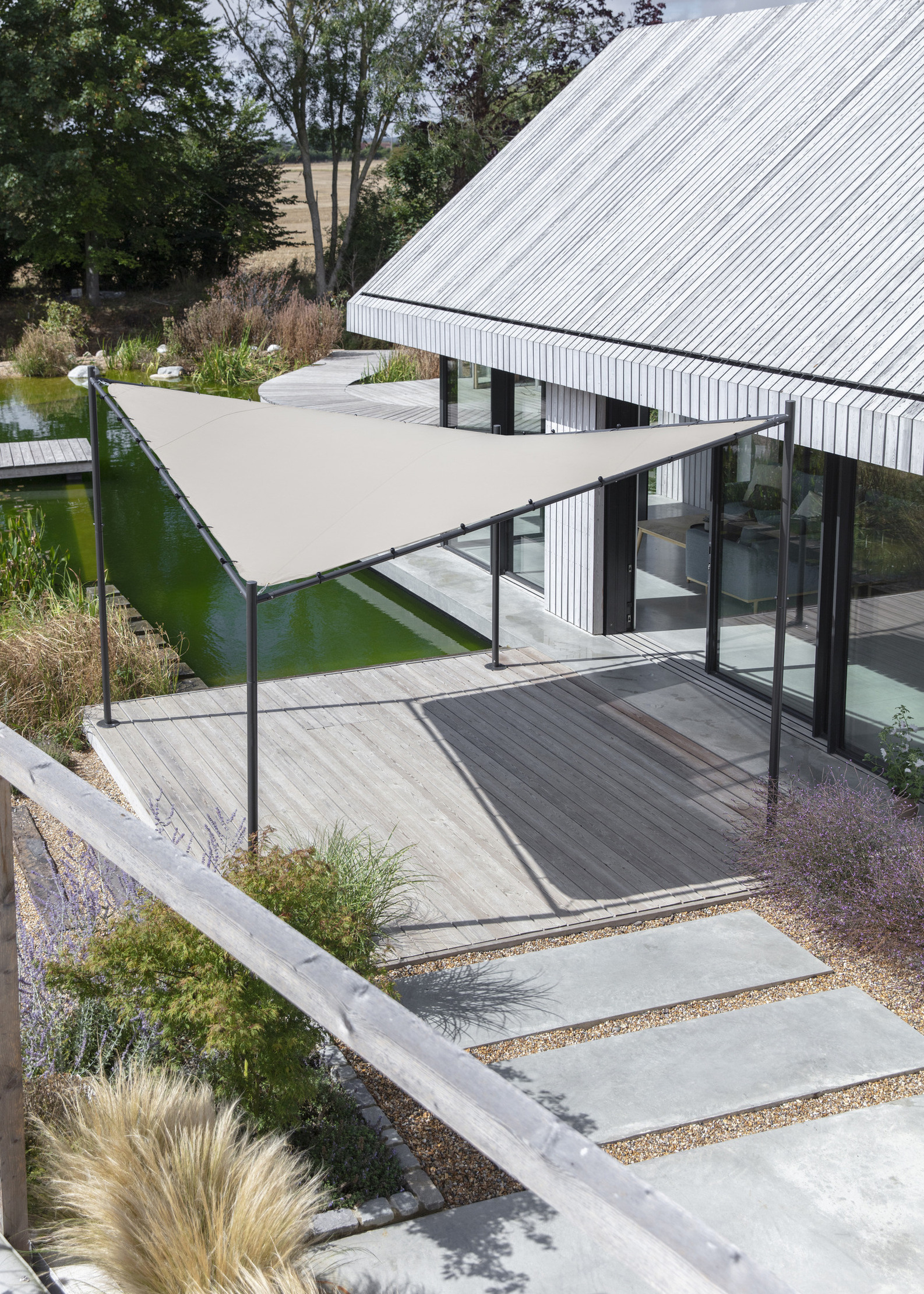 Triangular sail shade over timber decking in a backyard