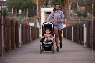 Woman running with a pram over a bridge