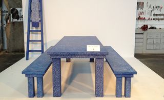 A blue table with two benches on either side. The furniture looks like it's scratched.