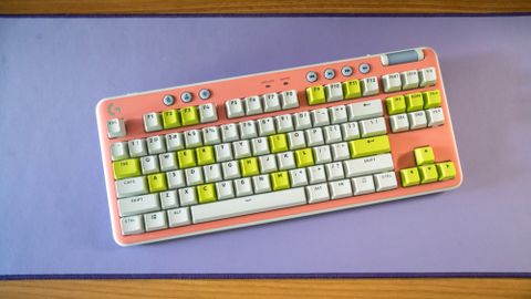 Logitech G715 TKL in its pink deck cover and white and green keys on purple Logitech desk mat