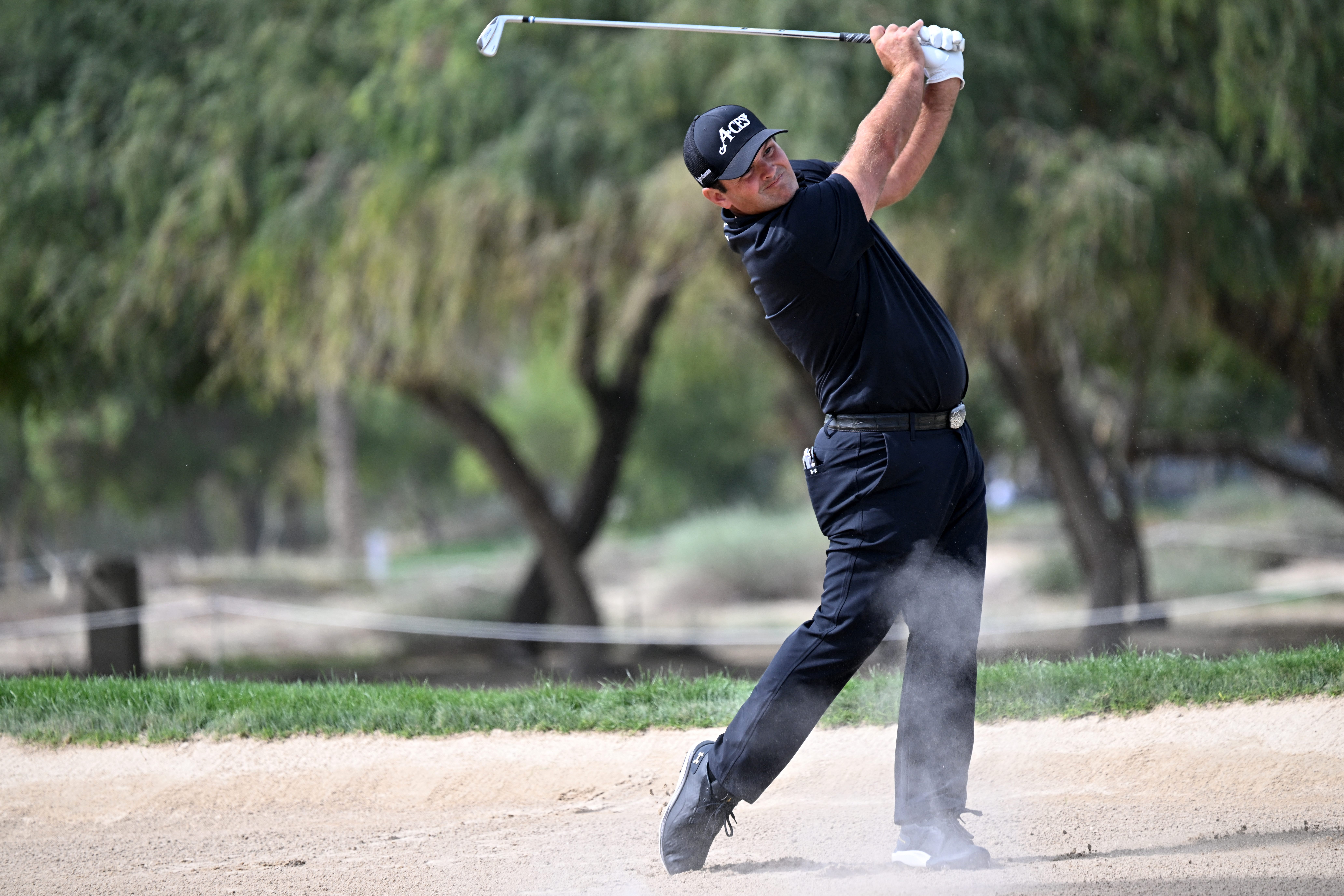 Patrick Reed hits an iron out of the desert