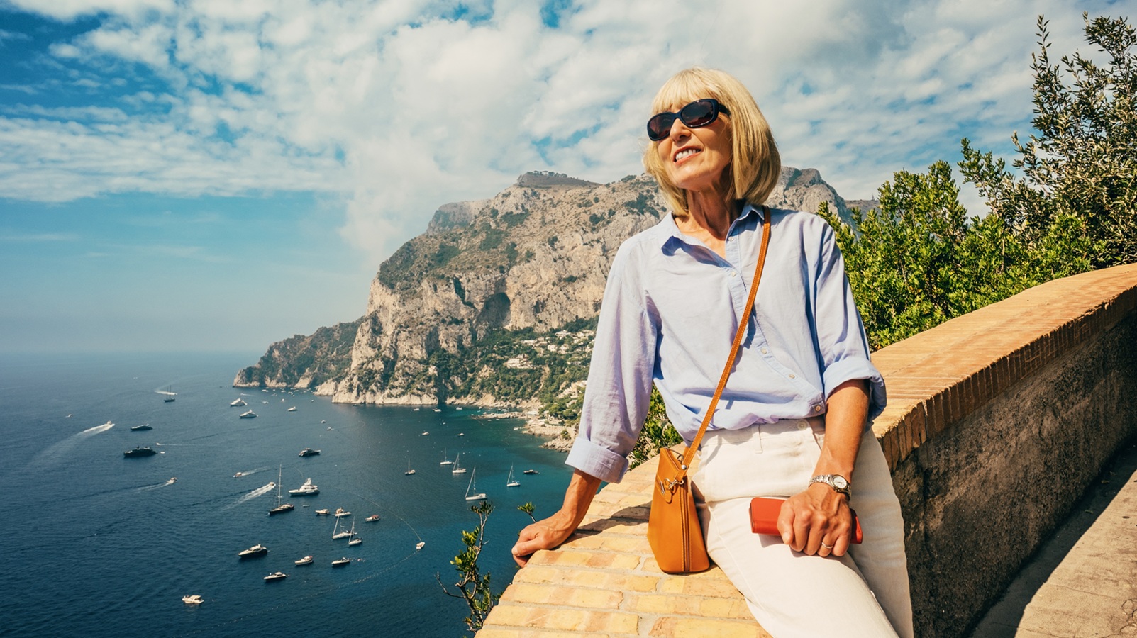 Female tourist admiring the view on the south east coast of the island of Capri, Bay of Naples, Italy.