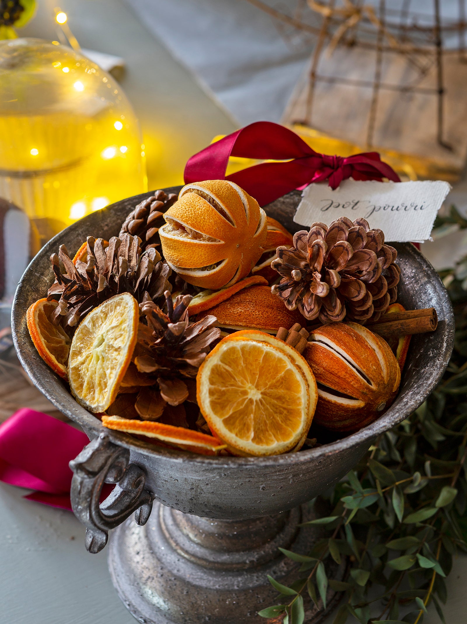 Close up of a bowl of dried oranges and pine cones, which make up a festive potpourri