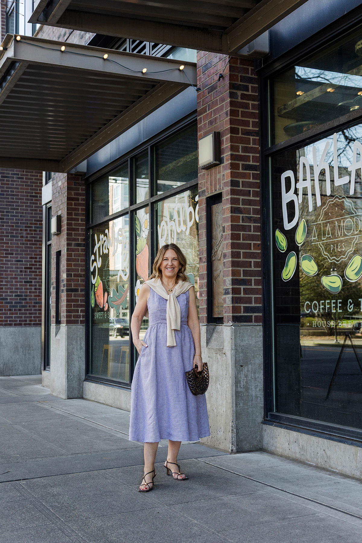 A former VIP Nordstrom stylist wearing a purple midi dress and strappy sandals.