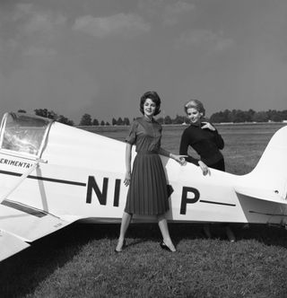 60s fashion - two women in front of a plane