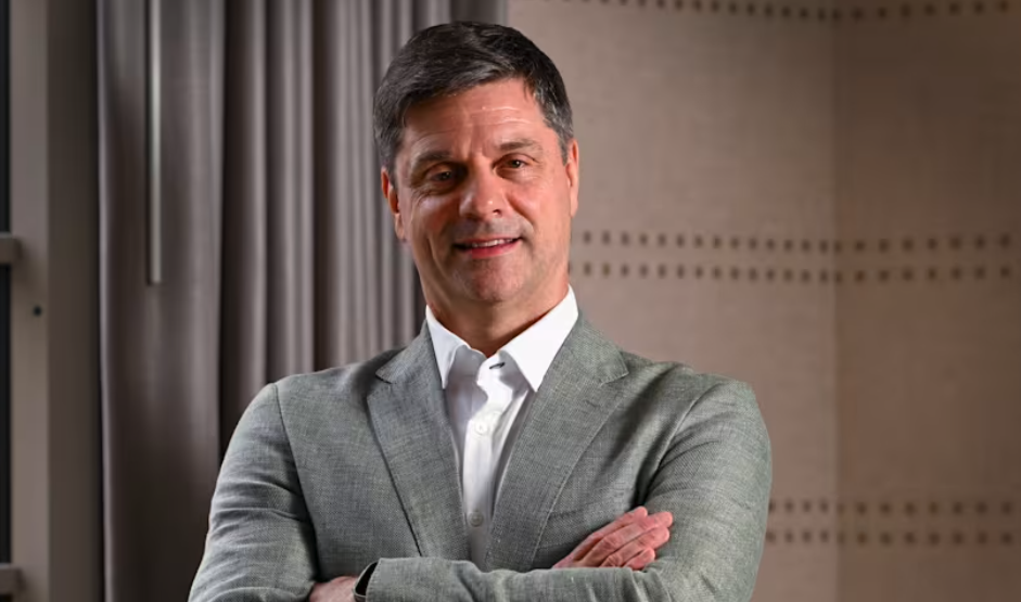 Brian Rolapp wearing a grey suit with his arms crossed