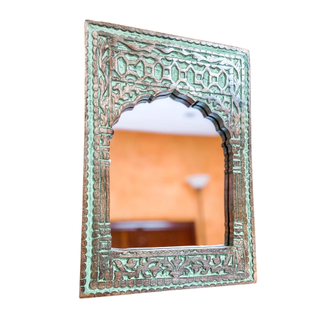 An ornate mint-colored, carved mirror in Indian style