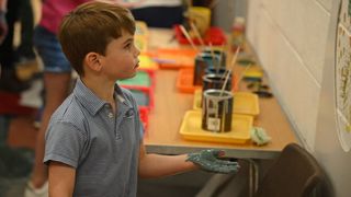 Prince Louis of Wales uses his hand to make a paint decorations on a wall while taking part in the Big Help Out