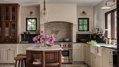 An Arts and Crafts kitchen with a mix of white and wood cabinets, black countertops, and a curved, freestanding wooden island