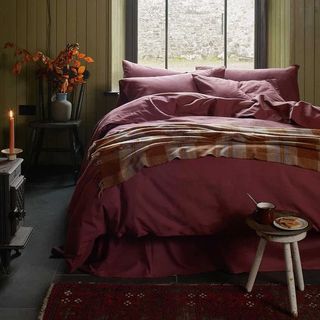 Berry red flannell bedding on a double bed with a wool throw over the end