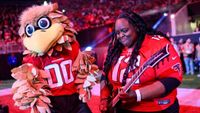 Diamond Rowe playing guitar next to a man dressed as a giant falcon