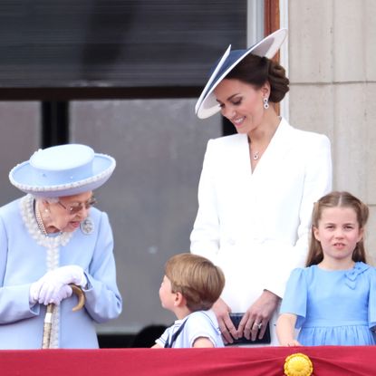 Queen Elizabeth talking to Prince Louis on the palace balcony as Princess Kate, Prince William, Princess Charlotte and Prince George look on