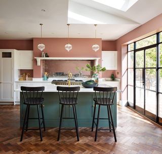 a pink open-plan kitchen with a blue island with a marble top, by Harvey Jones
