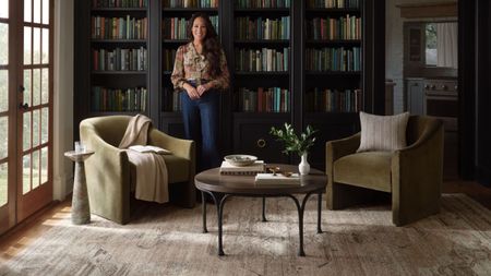 joanna gaines in a home library with two armchairs, a coffee table, and rug