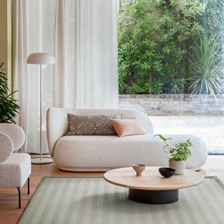 White sofa infront of large window with green stripe rug