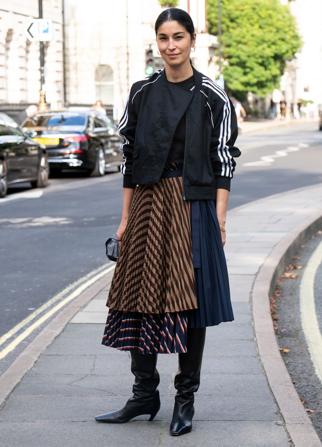 Caroline Issa wears a Sacai skirt, Adidas jacket and Khaite boots during London Fashion Week September 2021 on September 18, 2021 in London, England.