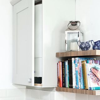 A hot water boiler stored in a tall wall kitchen cupboard unit, with shelves and wood worktop