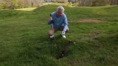 Golfer looking at ball in divot hole