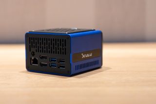 A blue and black Xulu XR1 Max mini PC on a wooden desk