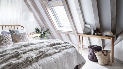 double bedroom with neutral colours sheepskin throw and whitewashed beams and rooflight