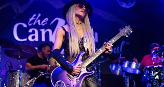 Orianthi wears a wide-brimmed hat and shades as she plays her purple "number one" PRS onstage at the Rock For Responders 2025 show in California.