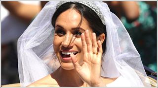 Meghan Markle smiles and waves, in her wedding dress, tiara and veil as she rides in the Ascot Landau carriage during the procession after getting married St George's Chapel, Windsor Castle on May 19, 2018 in Windsor, England