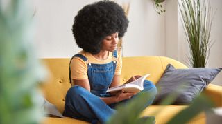 Woman enjoying reading a book while relaxing at home. Leisure activities concept