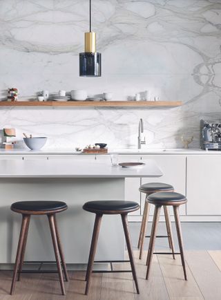 How to make a white kitchen look warm with a white marble backsplash and black barstools