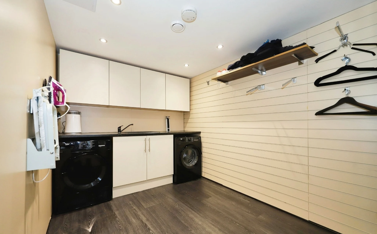 A white utility room with a washing machine underground