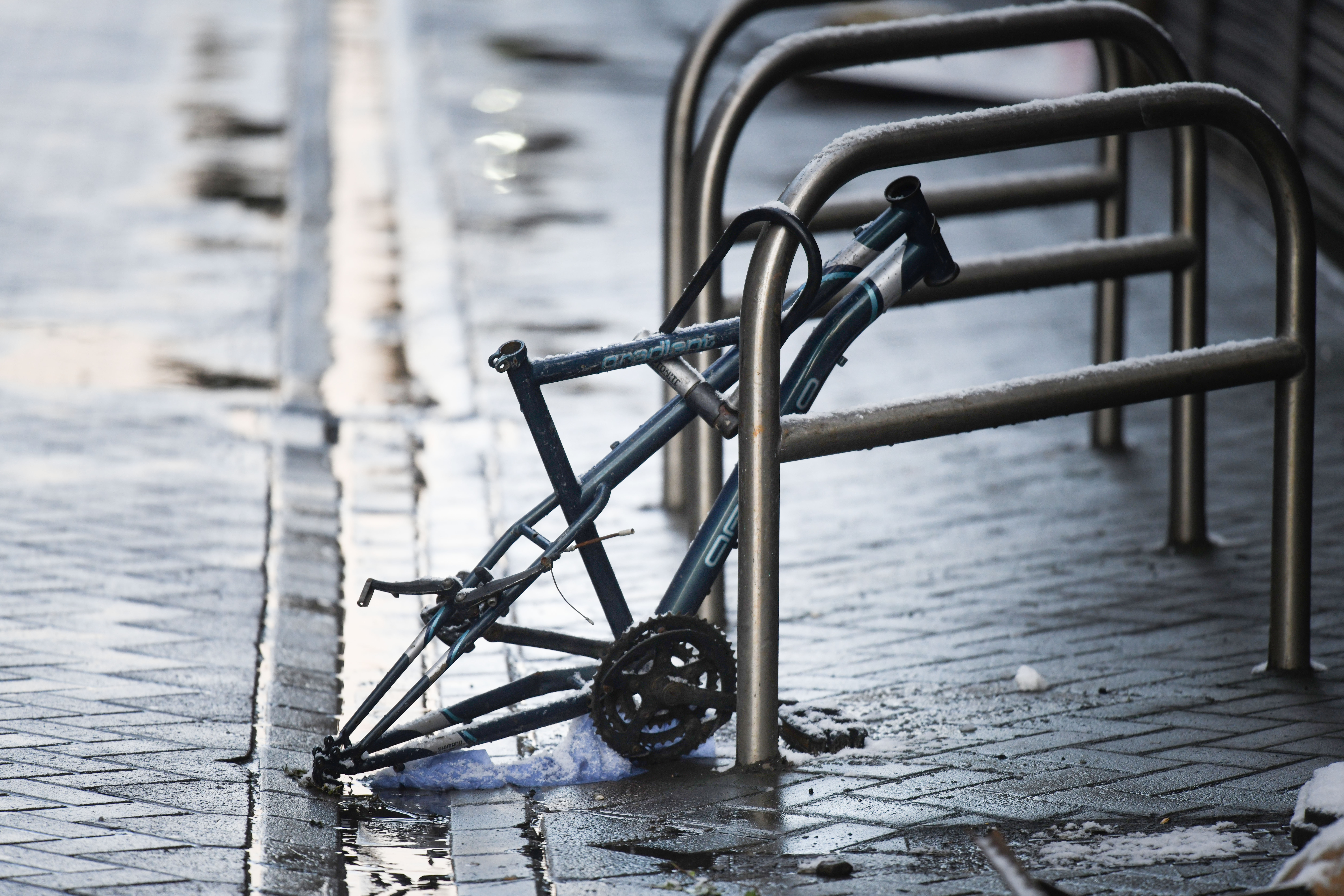A stripped bike frame locked to a bike stand