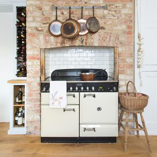 White range cooker in a brick chimney breast with a wine rack and wicker basket next to it