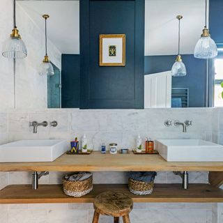 bathroom with wall mirror frame on blue wall and wash basin on wooden counter