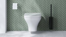 A toilet mounted on a bathroom wall with mint green tiles
