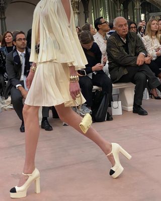 A S/S 25 Chanel silk chiffon cape worn with a matching miniskirt and platform heels.