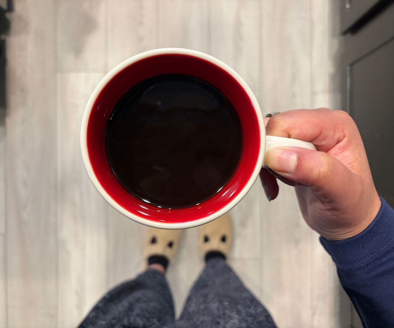 A red lined coffee mug viewed from above, with black coffee inside.