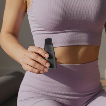 Lumen Metabolism tracker: A woman holding the device while wearing gym kit