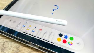 A second-generation Apple Pencil resting on an iPad Pro, with the Notes app open and a question mark drawn on the screen
