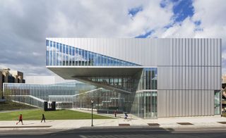 Exterior view of the with the building captured from the side and manicured lawn in front. Photographed during the day with the clouds in the sky in the background