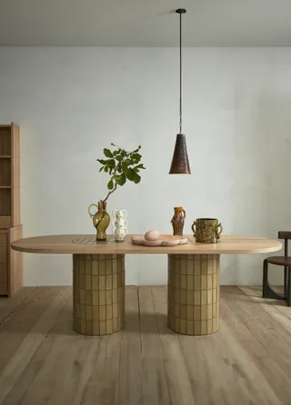 A table arrangement features contemporary design objects sitting on a organic shaped, tiled table in marble and ceramics.