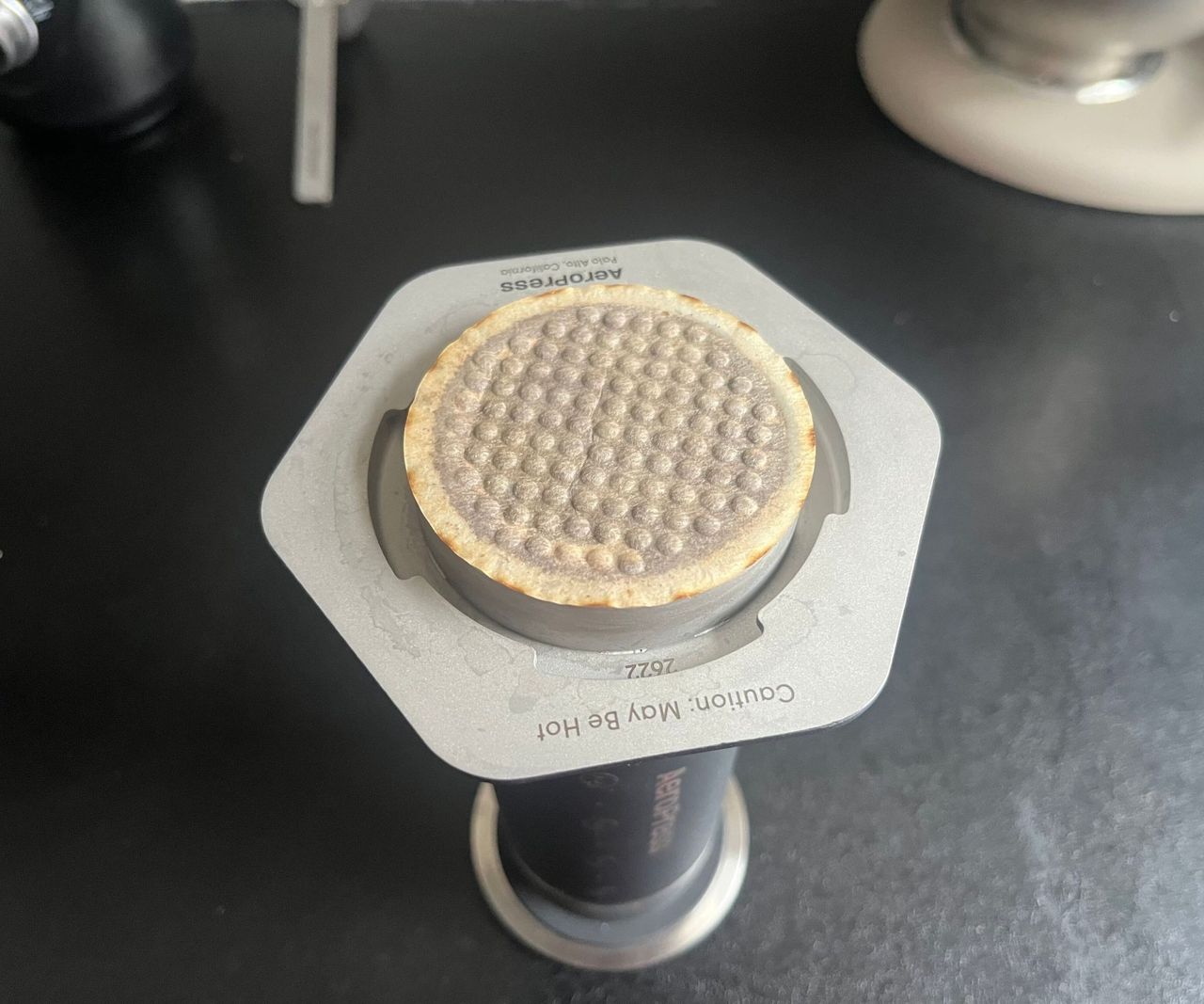 A AeroPress upside down with a coffee filter stuck to the end.