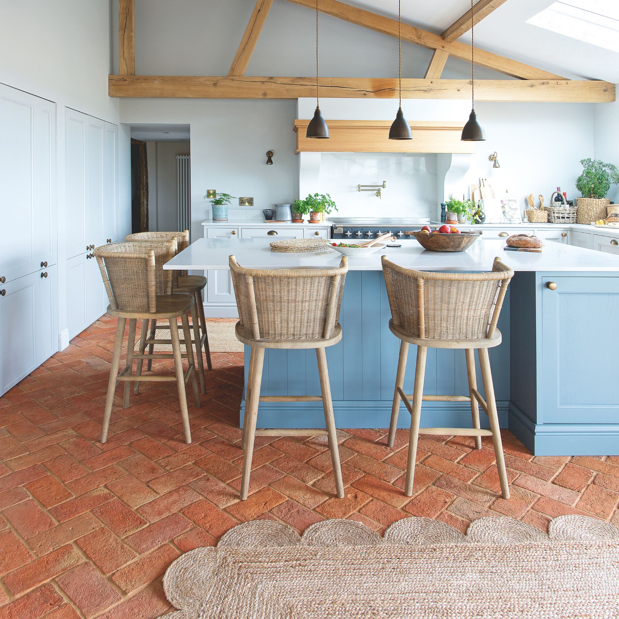 Large open-plan kitchen with blue cabinets and bar stools around a white kitchen island