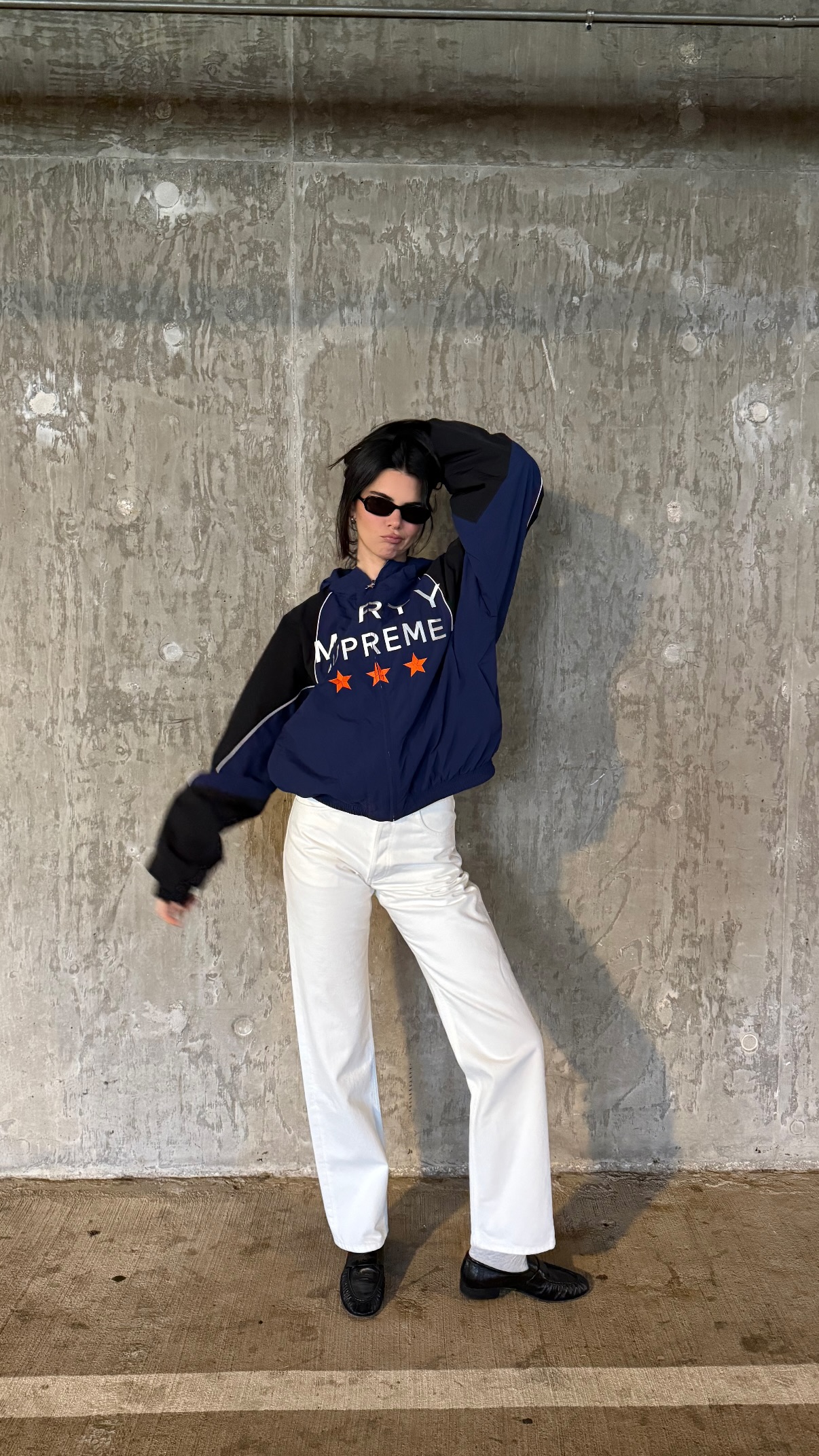 Kendall Jenner wears a track jacket, white pants, and black loafers