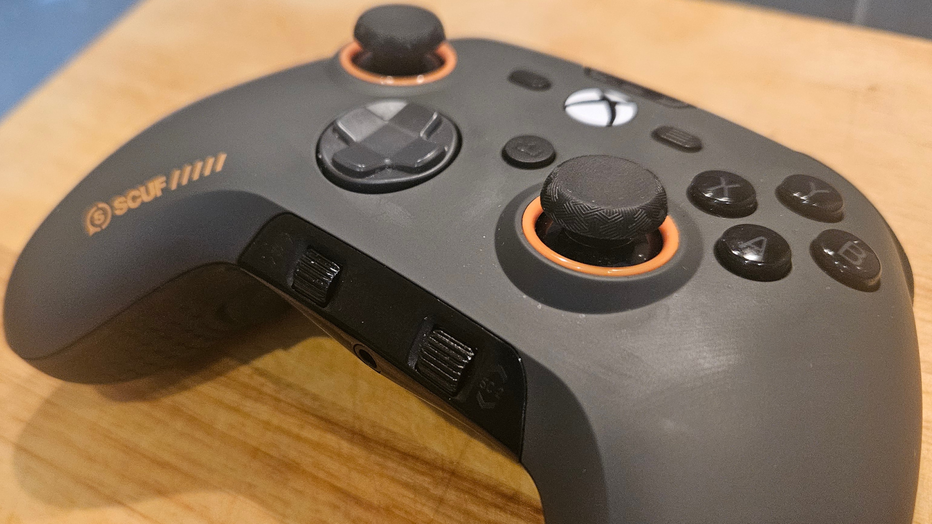 A photograph of a grey Scuf Valor Pro not plugged in, on a wooden surface